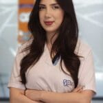 Female veterinarian wearing light pink scrubs with arms crossed standing in a clinic setting Dental merkez ağız ve diş sağlığı merkezi